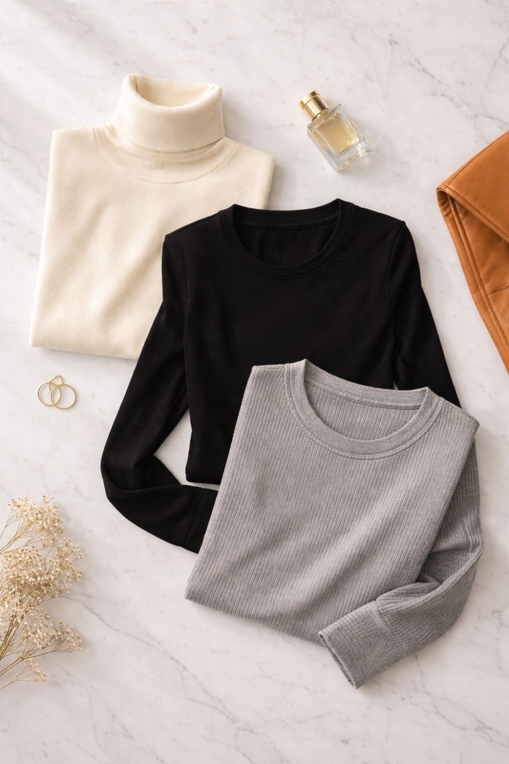 Flat lay of winter base layers including fitted turtleneck and merino wool tops for layering clothes for winter women