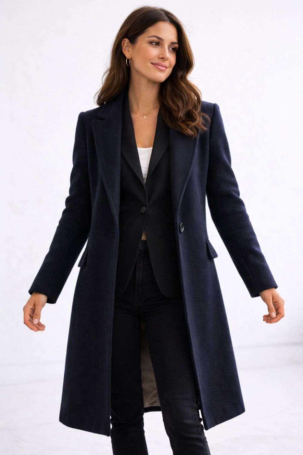 Woman in fitted black blazer under tailored navy wool coat demonstrating how to layer jackets without looking bulky